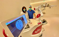 Top neurosurgeons Dr. Sharona Ben-Haim and Alexander Khalessi stand next to the ROSA robot